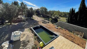 Un chantier de construction comprenant une piscine, une terrasse en bois et une zone en terre.