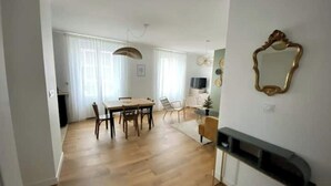 A modern living room with a dining area, wooden flooring, a fireplace, and a television. - Champagne! Spacious apartment (Reims)