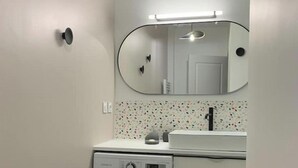 A compact bathroom with a washing machine, a sink, and a mirror. - Champagne! Spacious apartment (Reims)