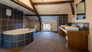 Un baño amplio con una bañera independiente, un tocador con espejo y una ducha.