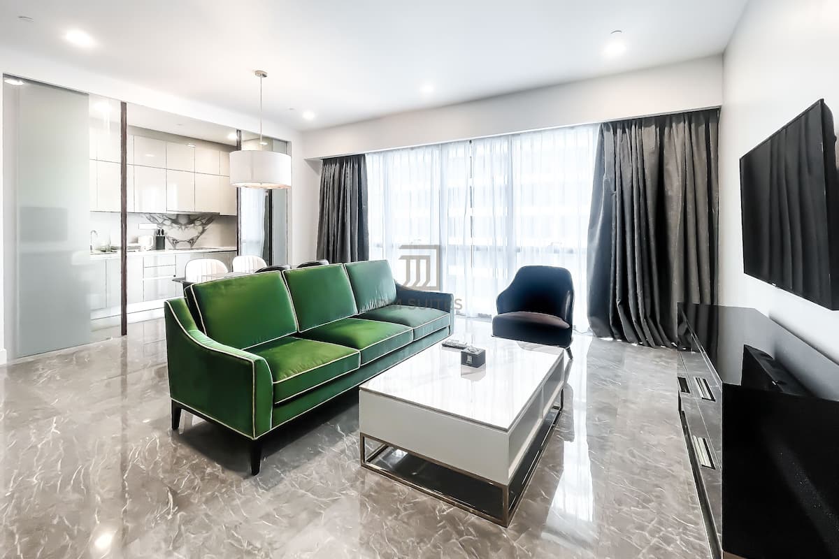 A modern living room with a green sofa, a white coffee table, and a flat-screen TV.