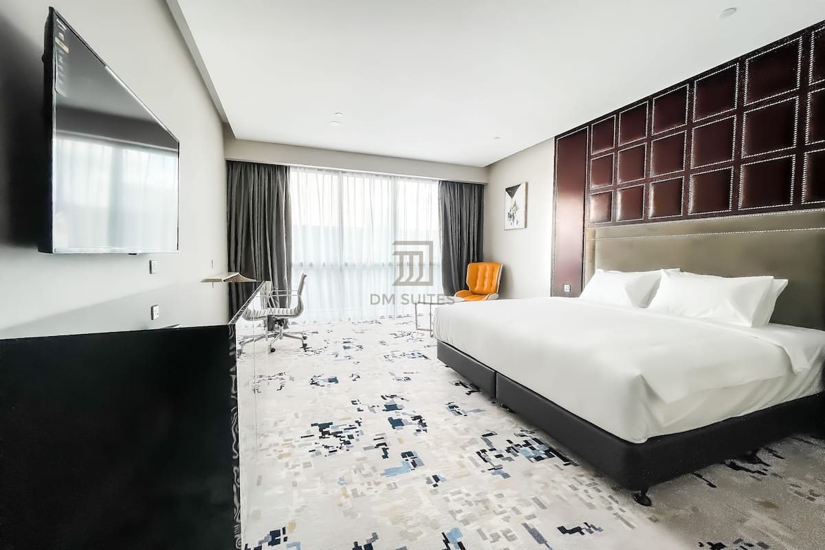 A hotel room with a large bed, a flat-screen TV, a desk, and a chair.