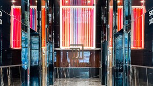 Eine moderne Hotelhalle mit Marmorboden, Glastrennwänden und farbenfrohen vertikalen Lichtpaneelen.