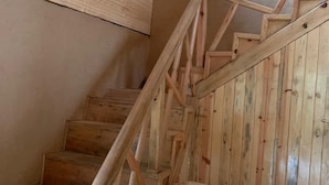A wooden staircase with a handrail and a wooden chair at the bottom. - Forest View farmhouse stay (Kosiyakutoli)