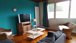 A living room with a television, sofa, and a small table. - Apartment 3 (Longchaumois)