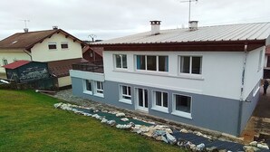 A two-story house with a sloped roof, multiple chimneys, and a balcony. - Apartment 3 (Longchaumois)