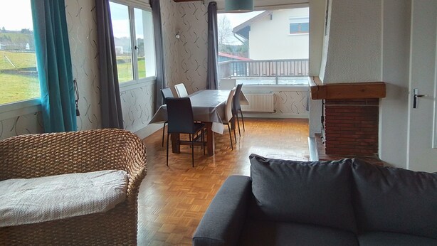 A cozy living room with a sofa, a dining table with chairs, and a fireplace. - Apartment 3 (Longchaumois)
