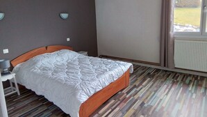 A bedroom with a bed, bedside tables, a window with curtains, and a radiator. - Apartment 3 (Longchaumois)