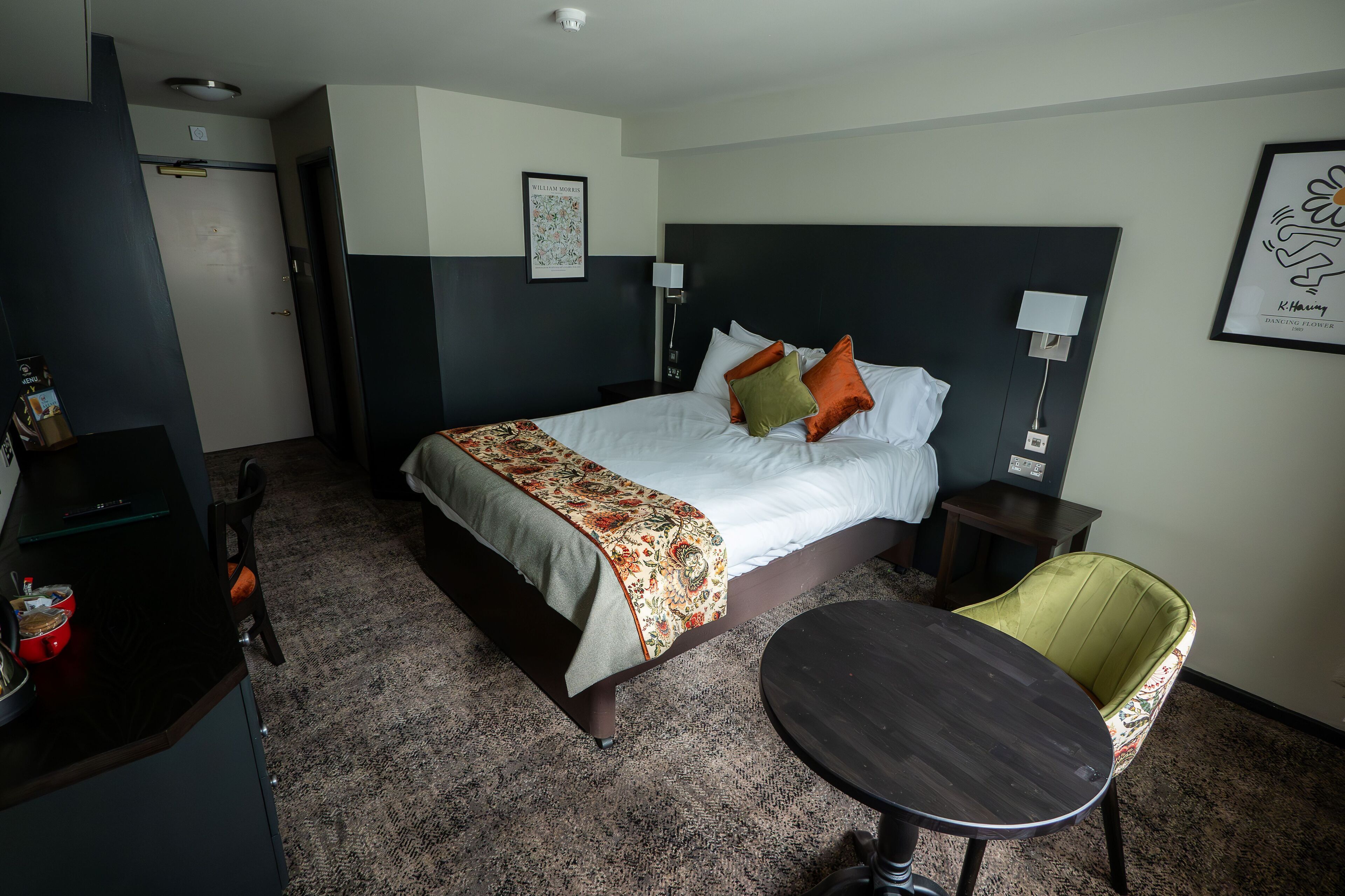 Ein Hotelzimmer mit Bett, Nachttischen, Schreibtisch, Stuhl und kleinem Tisch.