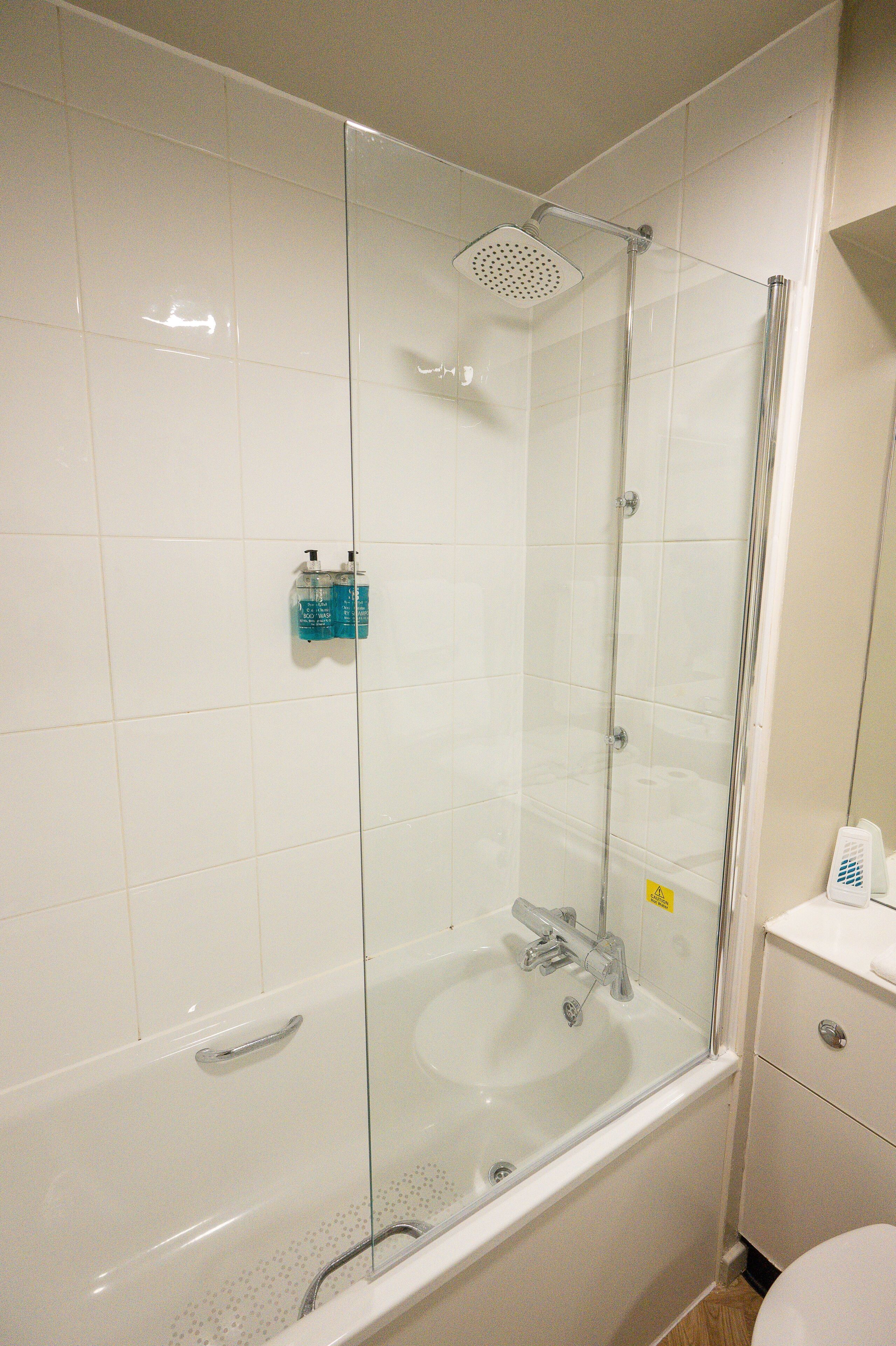 A bathroom with a glass-enclosed shower, a bathtub, and a sink.