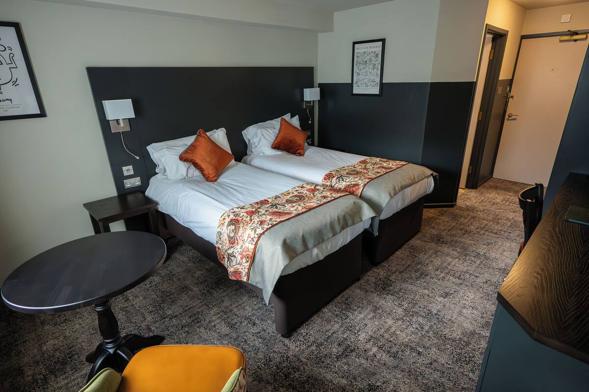 A hotel room with a bed, a small table, and a chair.