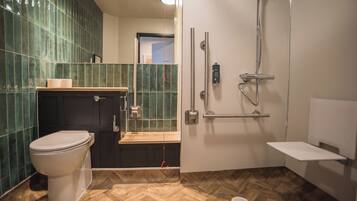 A modern bathroom with a toilet, a shower with a grab bar, and a bench.