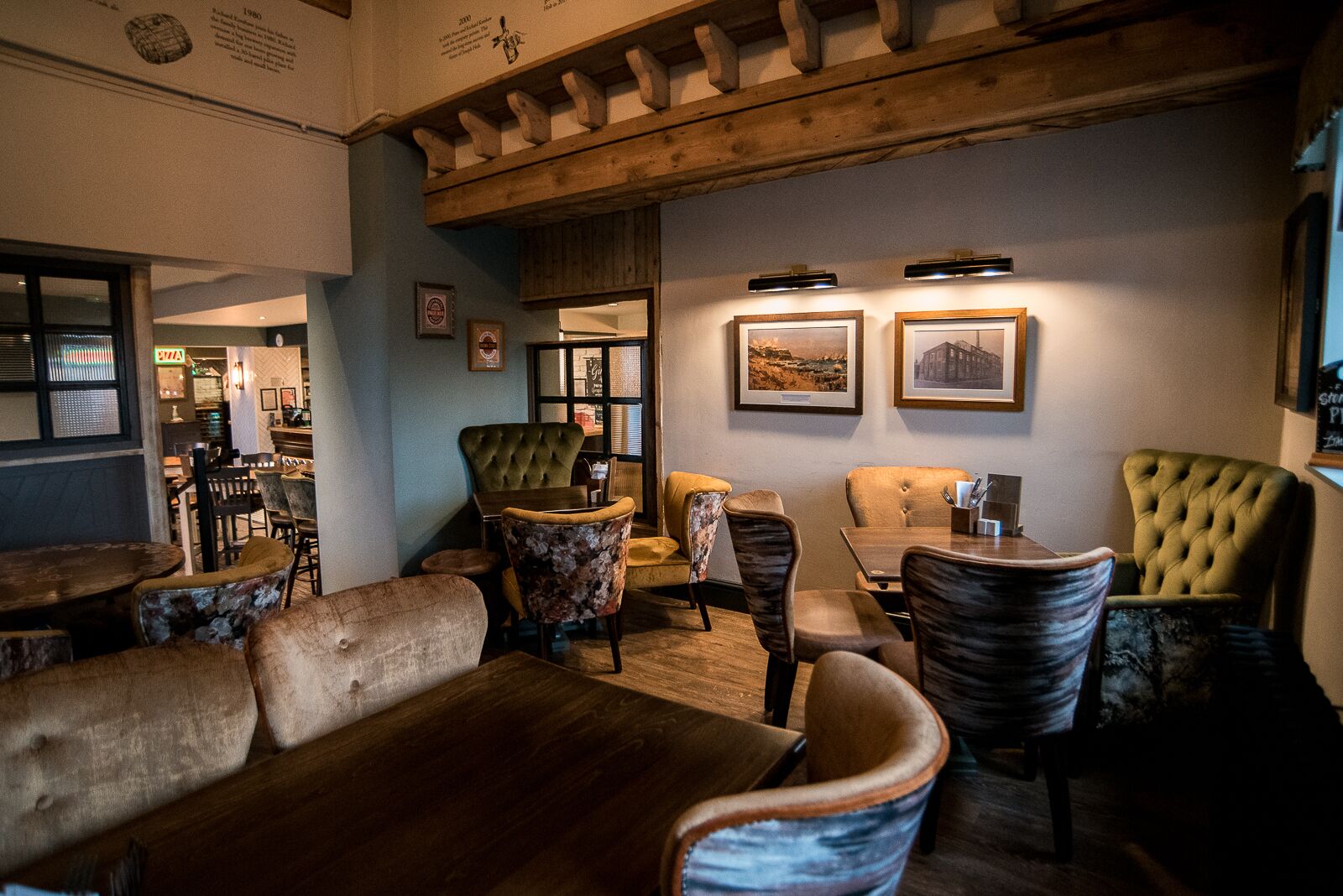 A cozy lounge area with a wooden ceiling, plush seating, and framed pictures on the walls.