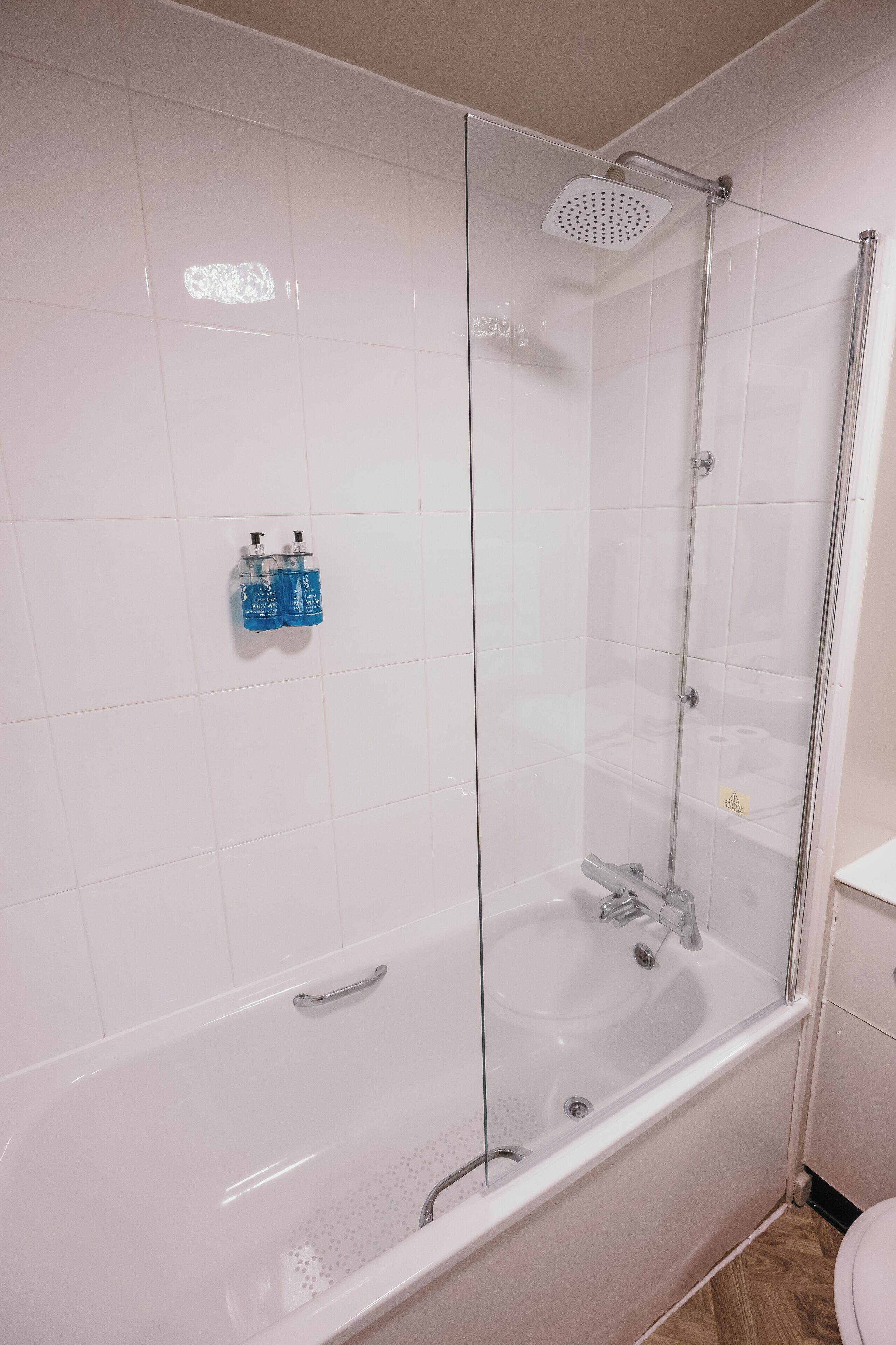 A modern bathroom with a glass-enclosed shower, a white bathtub, and a toilet.