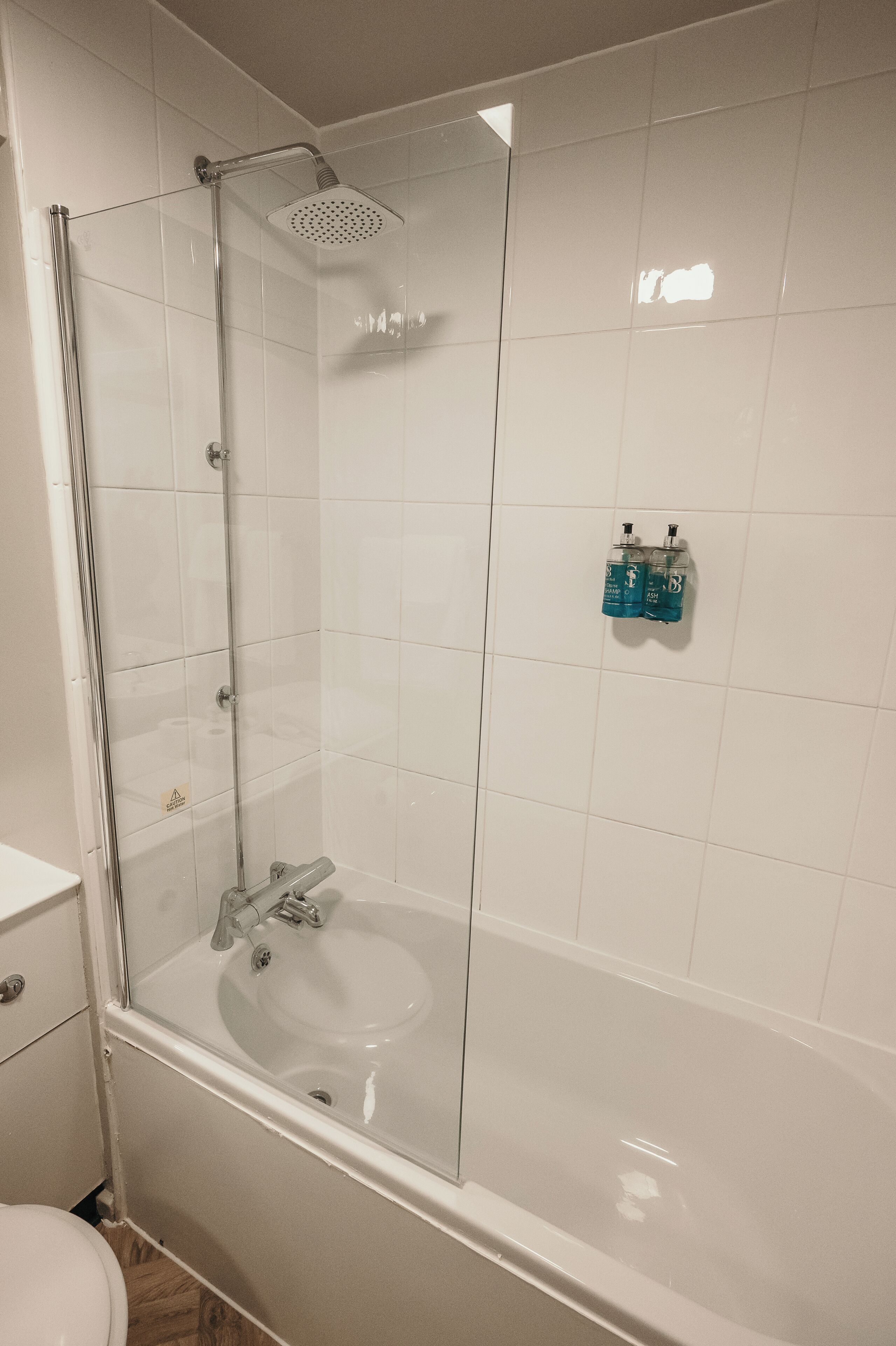 A bathroom with a glass-enclosed shower, a white sink, and a toilet.