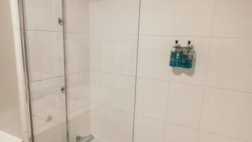 A bathroom with a glass-enclosed shower, a white sink, and a toilet.