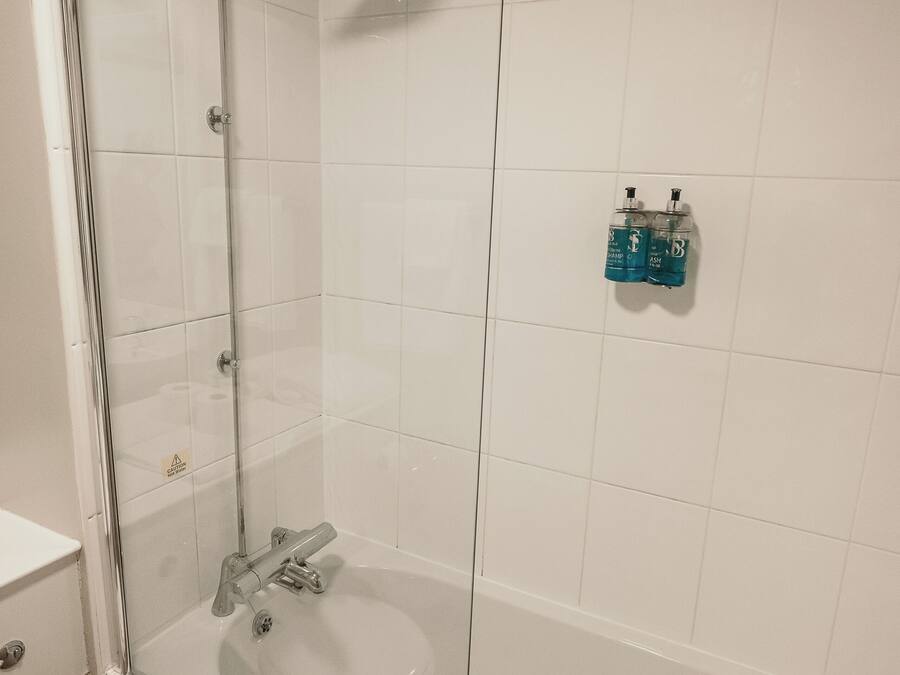 A bathroom with a glass-enclosed shower, a white sink, and a toilet.