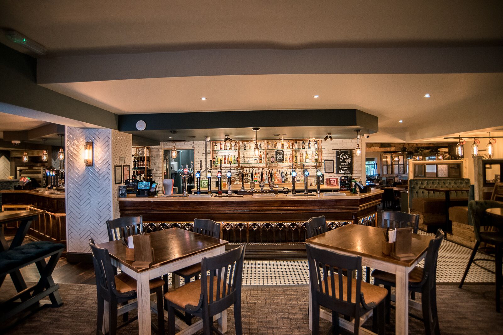 A bar area with a counter, bar stools, and a seating area with tables and chairs.