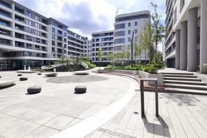 Experience the urban oasis with a spacious courtyard featuring spherical seating areas and lush landscaping.