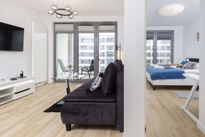 Relax in this stylish living space with a sofa, flat-screen TV, and a view of the surrounding buildings.