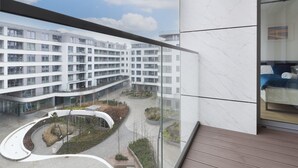 Un edificio moderno con fachada de vidrio curva, un patio con jardines y vistas a una zona residencial.