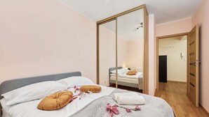A bedroom with a bed, a wardrobe, and a mirror. - Spacious Apartment | Balcony, Parking, Workspace (Wroclaw)