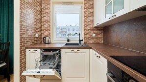 A kitchen with a brick wall, a window, and white cabinets. - Spacious Apartment | Balcony, Parking, Workspace (Wroclaw)