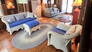Ein gemütliches Blockhaus-Interieur mit einer großen Couch, zwei Sesseln und einem Esstisch.