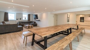 Un salon moderne avec une table à manger en bois, un canapé et un téléviseur fixé au mur.