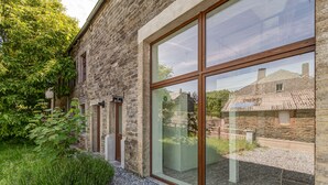 Un bâtiment en pierre doté de grandes fenêtres et d’un chemin bordé de gravier.
