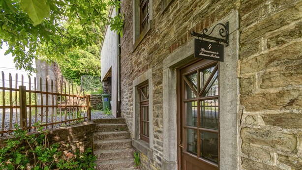 Un bâtiment en pierre avec une porte en bois et une enseigne sur laquelle on peut lire : « Bienvenue à la Maison Malan ».