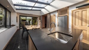 A modern kitchen with a large island, a skylight, and a view of the outdoors.