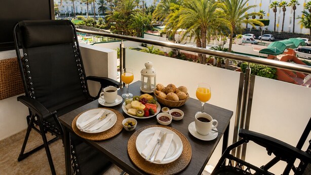 Ein Balkon mit einem Tisch, gedeckt für ein Frühstück, einschließlich Früchte, Nüsse und Getränke.