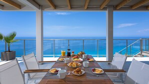 Une table à manger dressée pour le petit-déjeuner, avec une vue sur l’océan.