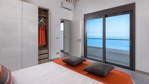 Une chambre à coucher comprenant un lit, une armoire et une porte-fenêtre coulissante donnant sur le balcon.