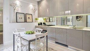 Eine moderne Küche mit einer zentralen Kochinsel, weißen Schränken und gerahmten Kunstwerken an den Wänden.