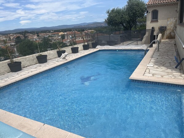 A swimming pool with a view of a town and mountains in the background.
