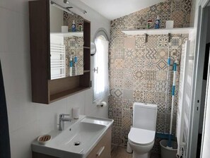 Une salle de bain avec un lavabo, un miroir, des toilettes et des carreaux décorés.