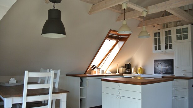 Une cuisine avec des meubles blancs, un plan de travail en bois et une fenêtre au-dessus de l’évier.