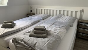 Un lit simple avec une literie blanche et deux tables de chevet avec des lampes.