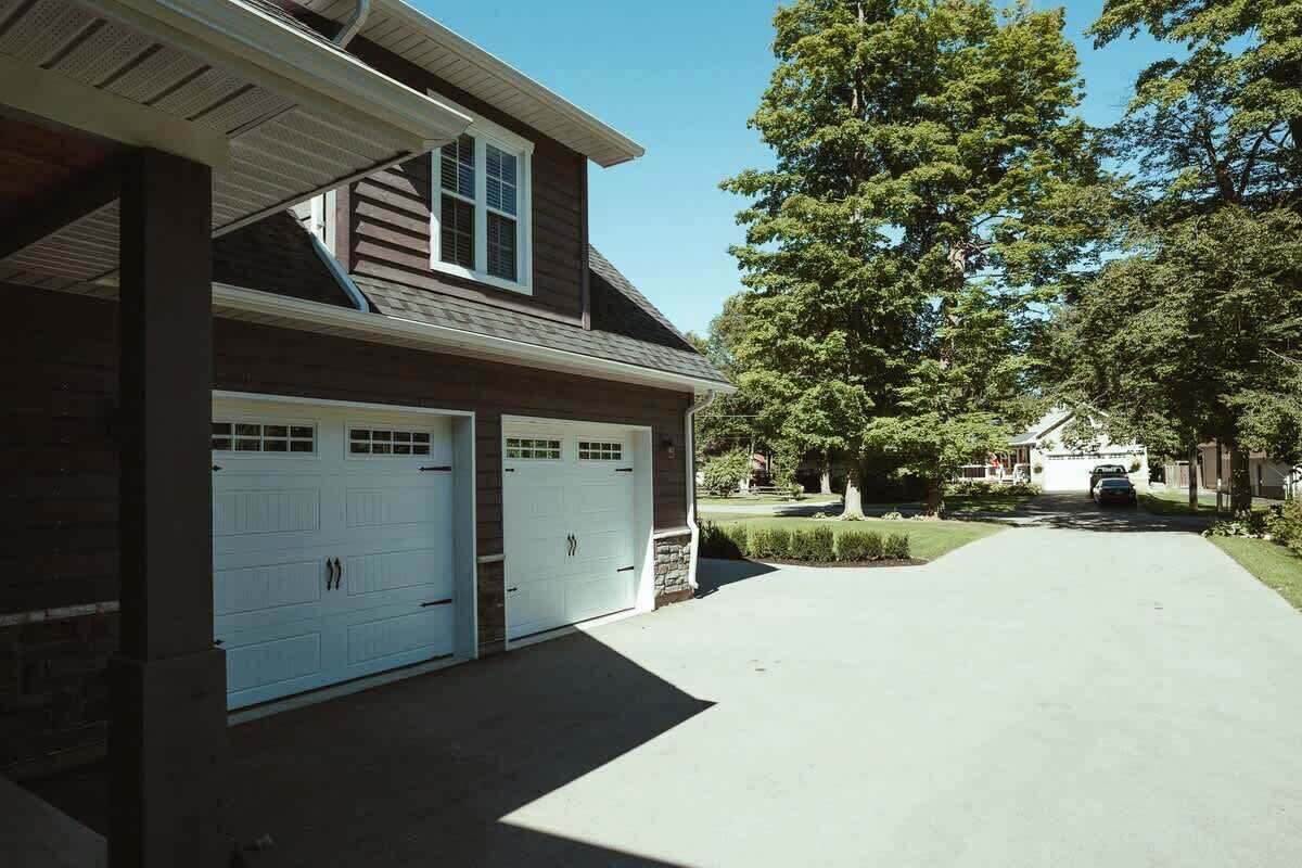 A two-story house with a covered garage and a driveway leading to the front door.
