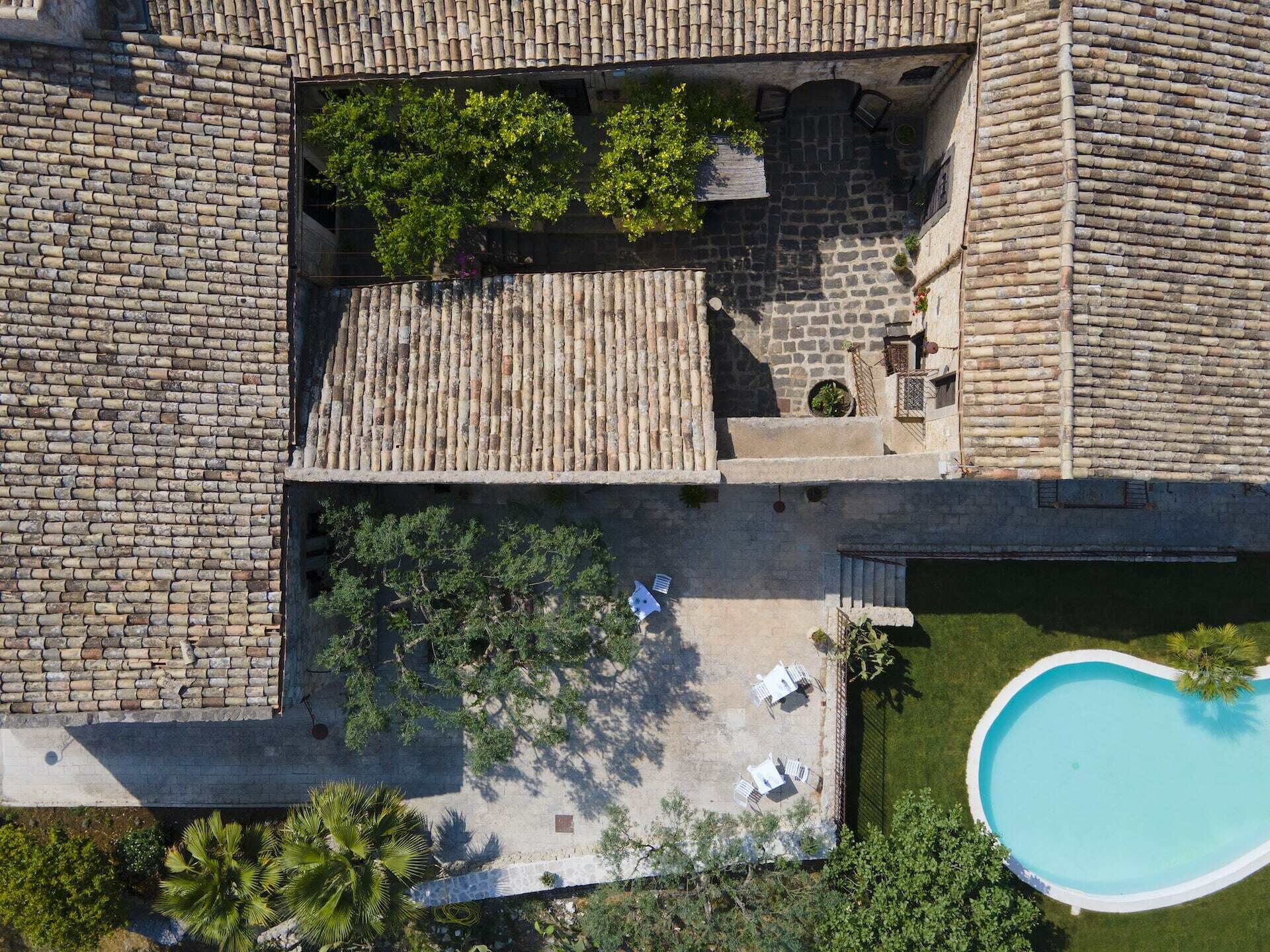 An aerial view of a courtyard with a swimming pool, stone walls, and outdoor seating.