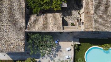 An aerial view of a courtyard with a swimming pool, stone walls, and outdoor seating.
