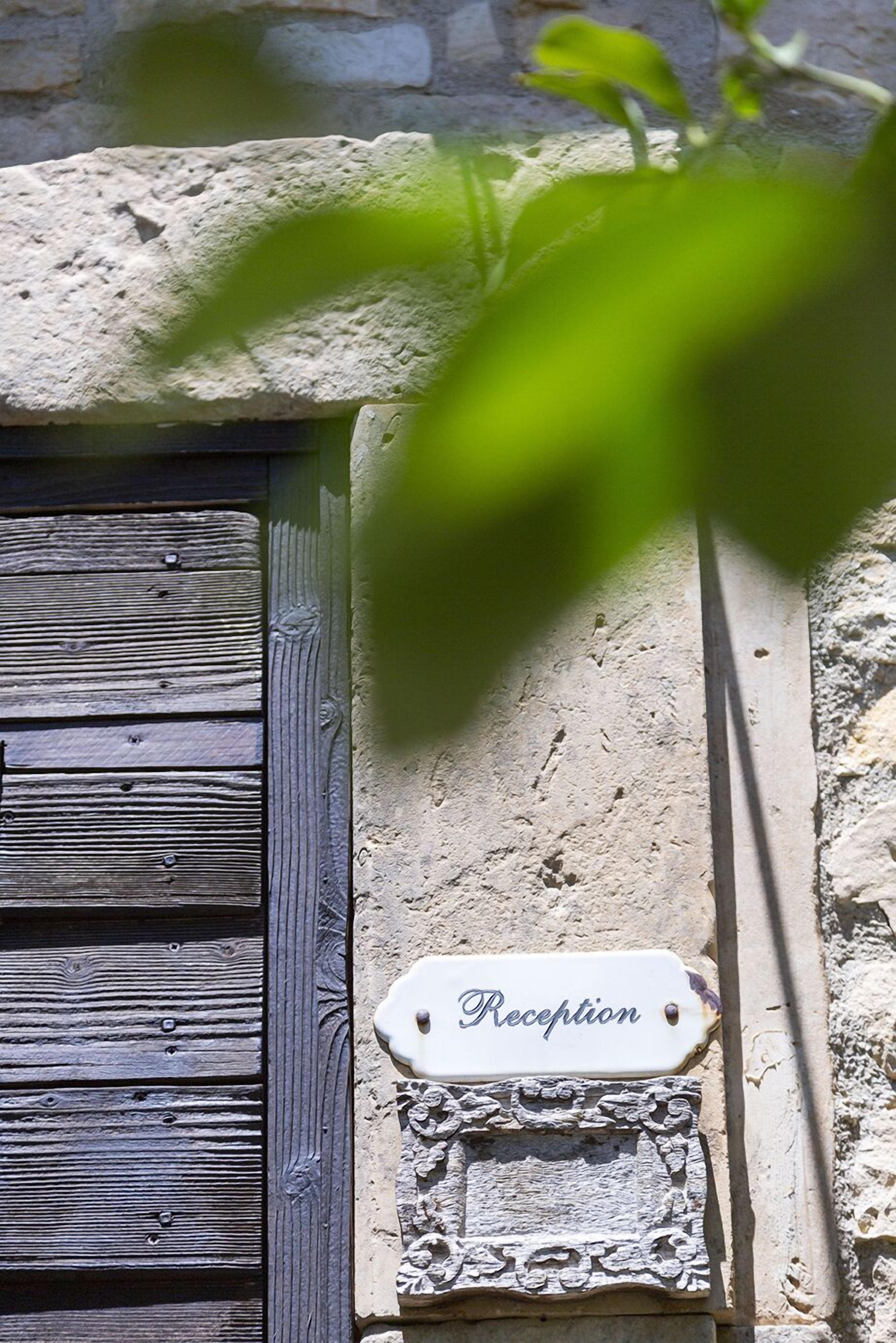 Una puerta de madera rústica con un letrero que dice 'Reception' encima, frente a un muro de piedra con textura.
