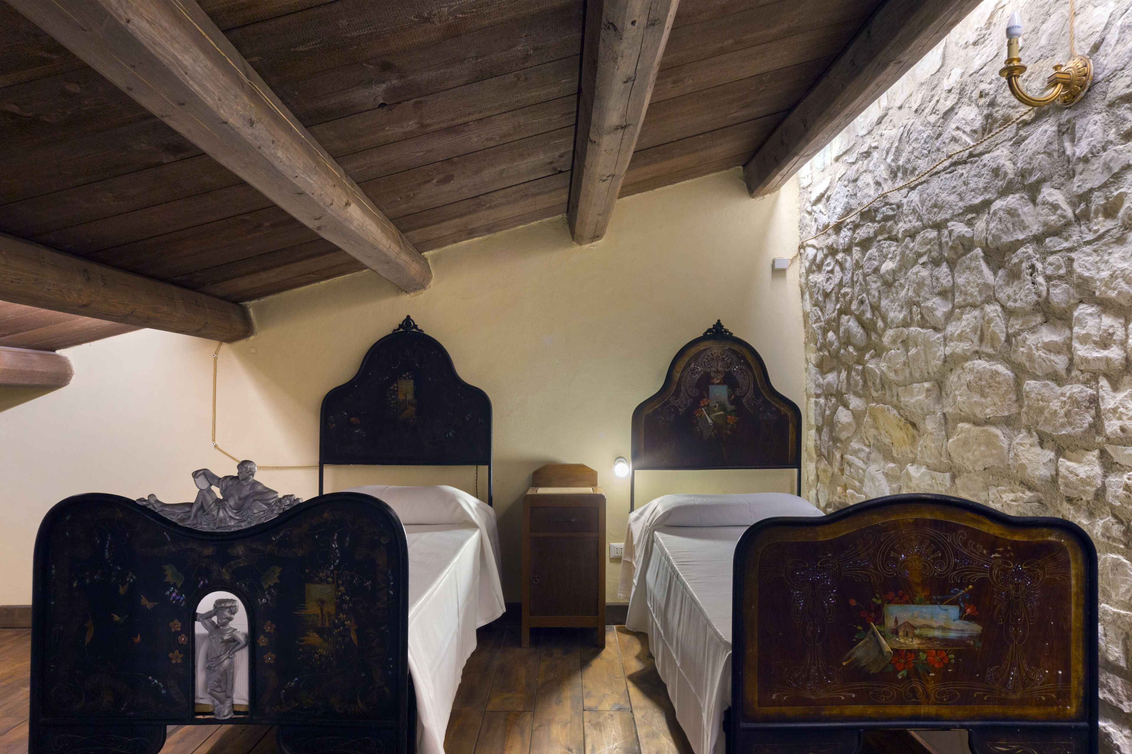 A room with two wooden beds, a stone wall, and a wooden ceiling.