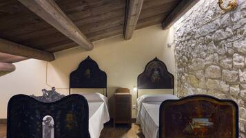 A room with two wooden beds, a stone wall, and a wooden ceiling.