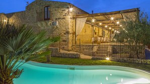A stone building with a pool, outdoor seating, and a covered patio area. - Masseria Fortificata Lo Zafferaneto  (Buccheri)