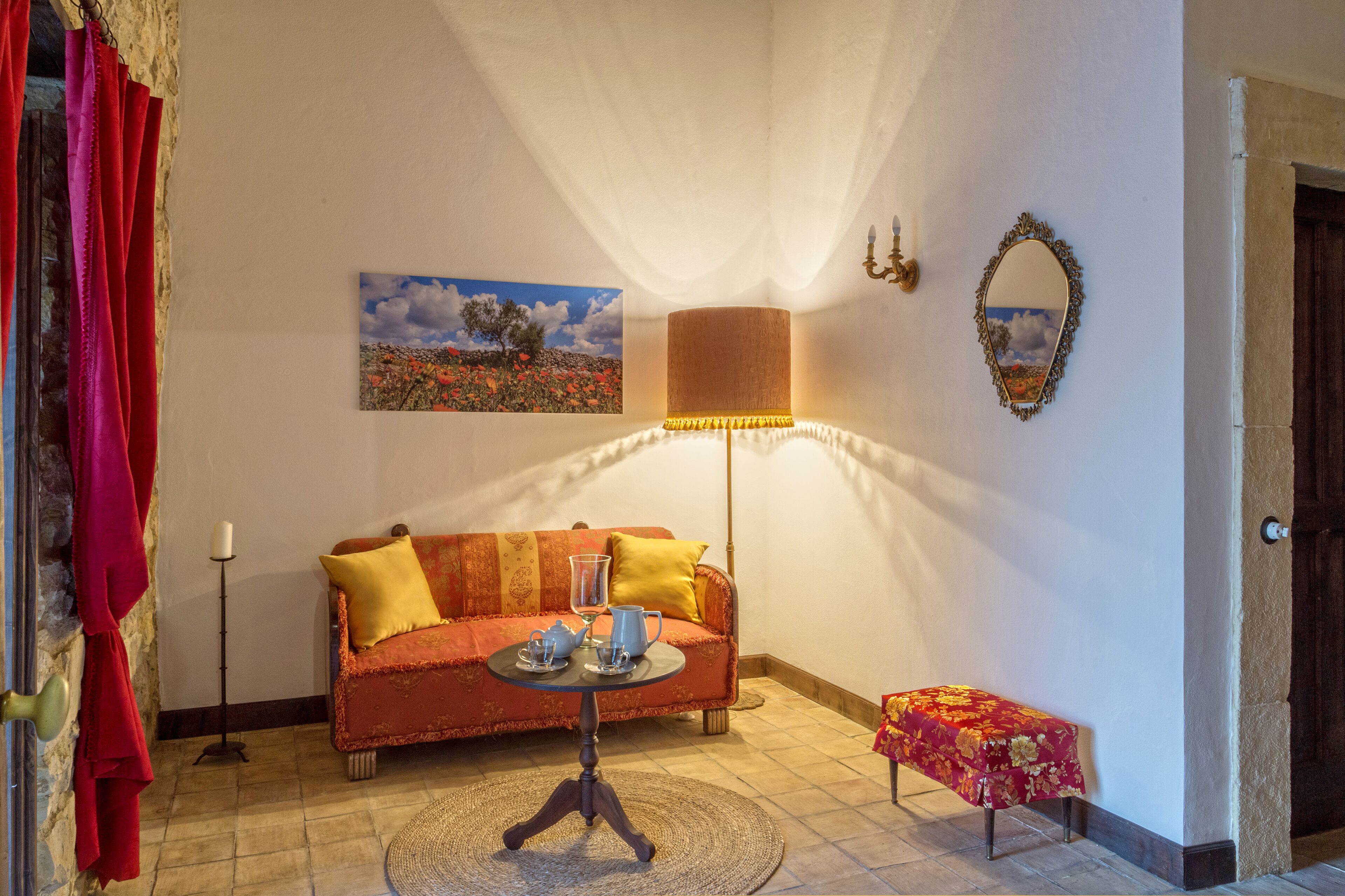 Ein gemütliches Wohnzimmer mit Sofa, einem kleinen Tisch mit Lampe, einem Bild an der Wand und einer Tür.