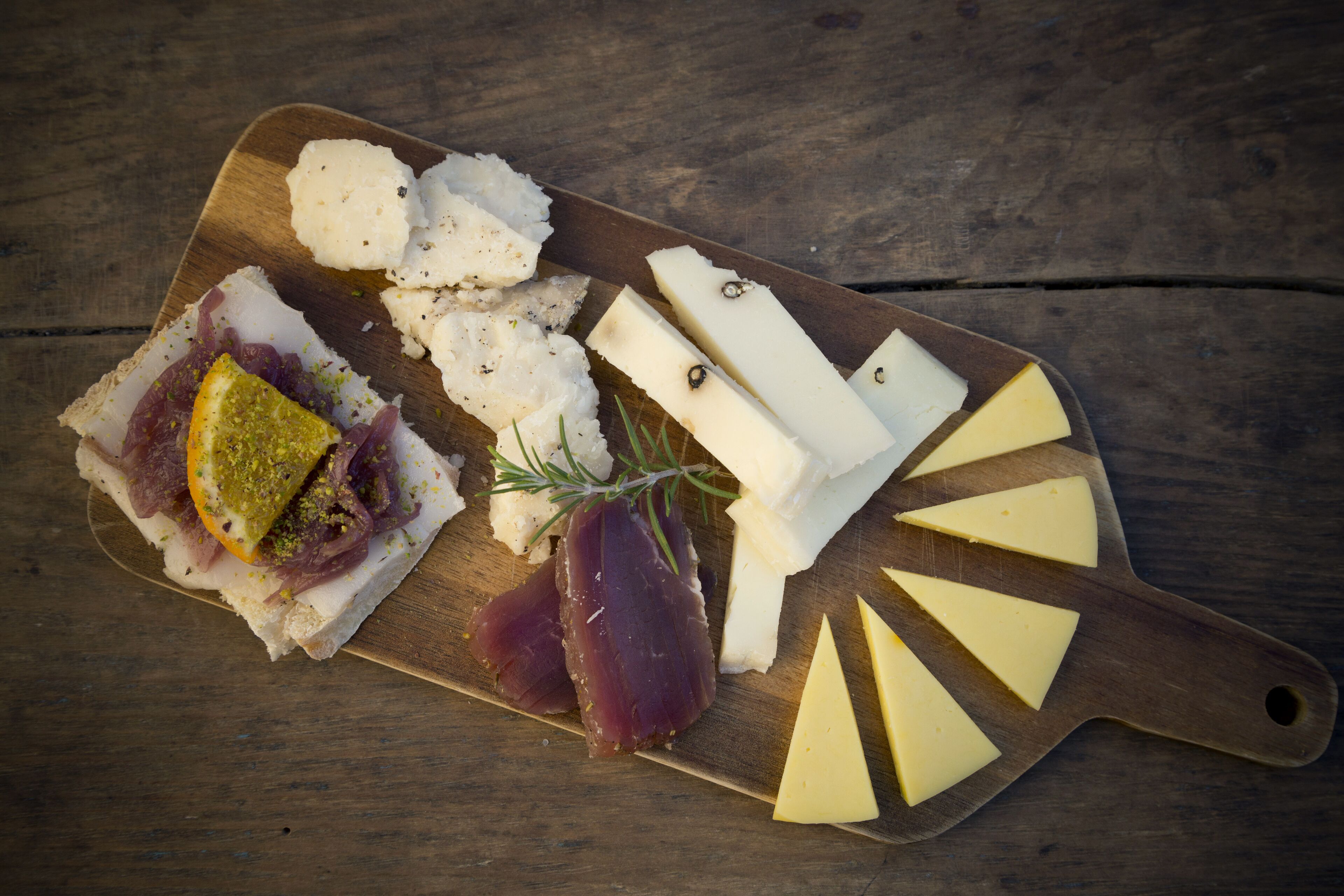 Une planche en bois garnie de différents fromages et de charcuteries.