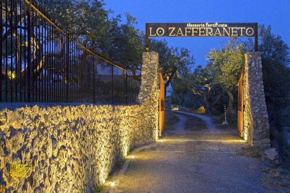 A stone gate with a sign reading "Masserie fortificata LO ZAFFERANETO" leading to a path.